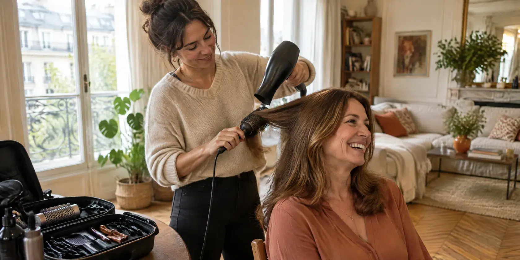 Une coiffeuse à domicile réalise un brushing chez un client, dans son salon
